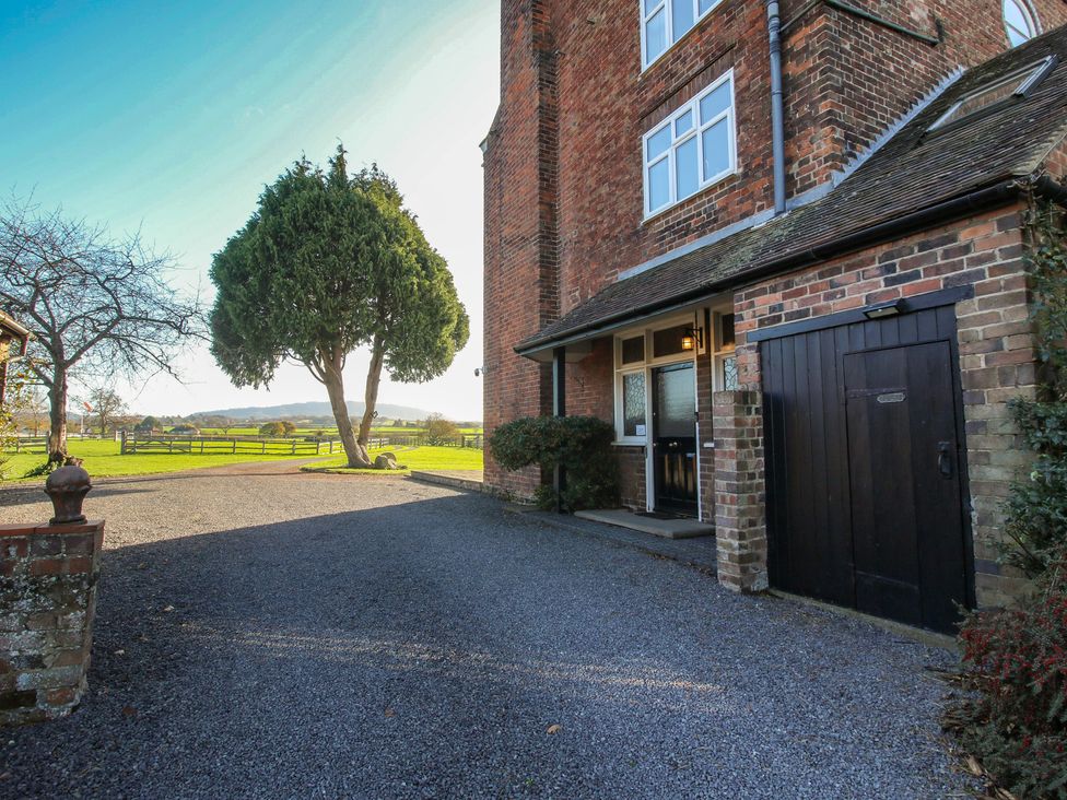 A gravel driveway with a brick house and tree at The Mill House