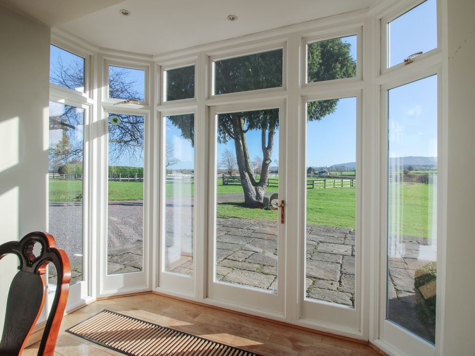 A sunroom with windows and a door overlooking a garden at The Mill House 