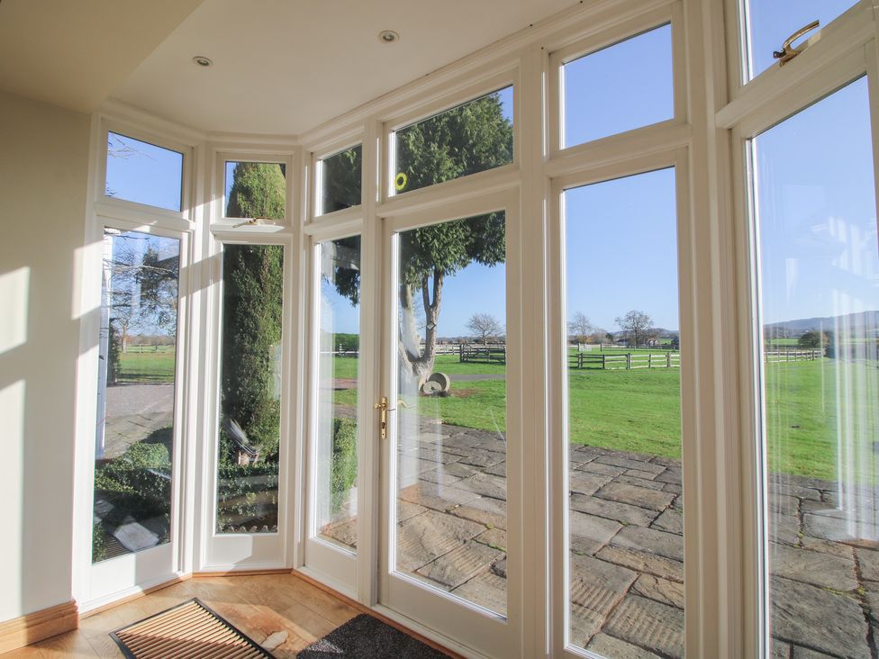 A conservatory with large windows and a view of the garden at The Mill House