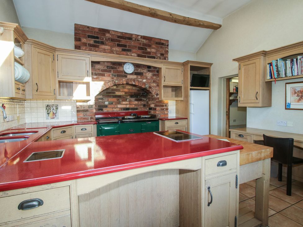 A kitchen with a red countertop and brick wall at The Mill House
