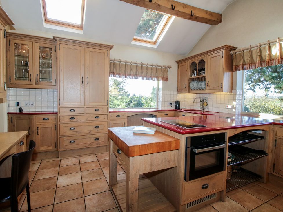 A kitchen with wood cabinets and an island at The Mill House