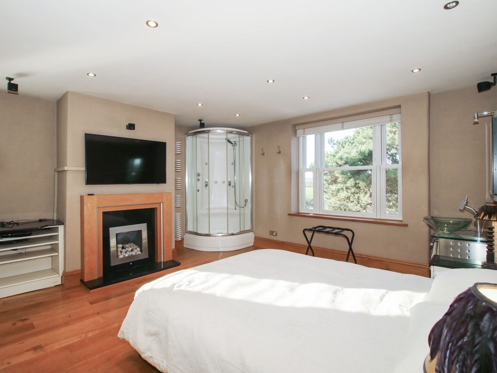 A bedroom with a shower and television at The Mill House in 