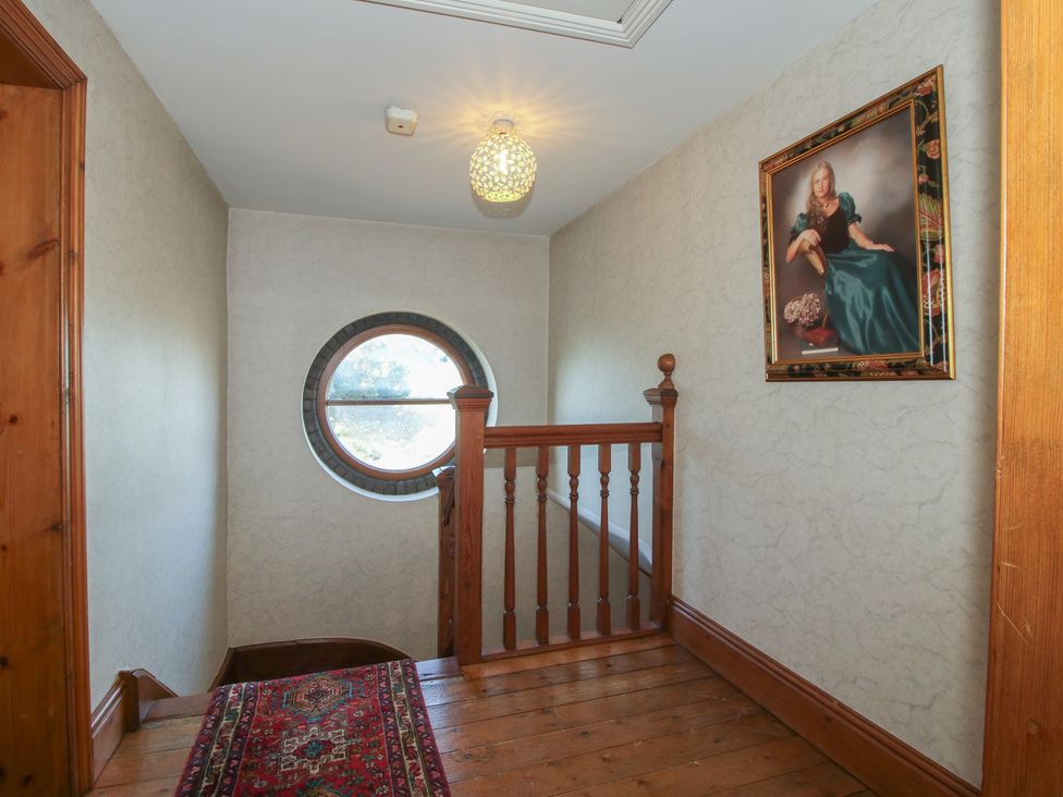 A hallway with a staircase and round window at The Mill House