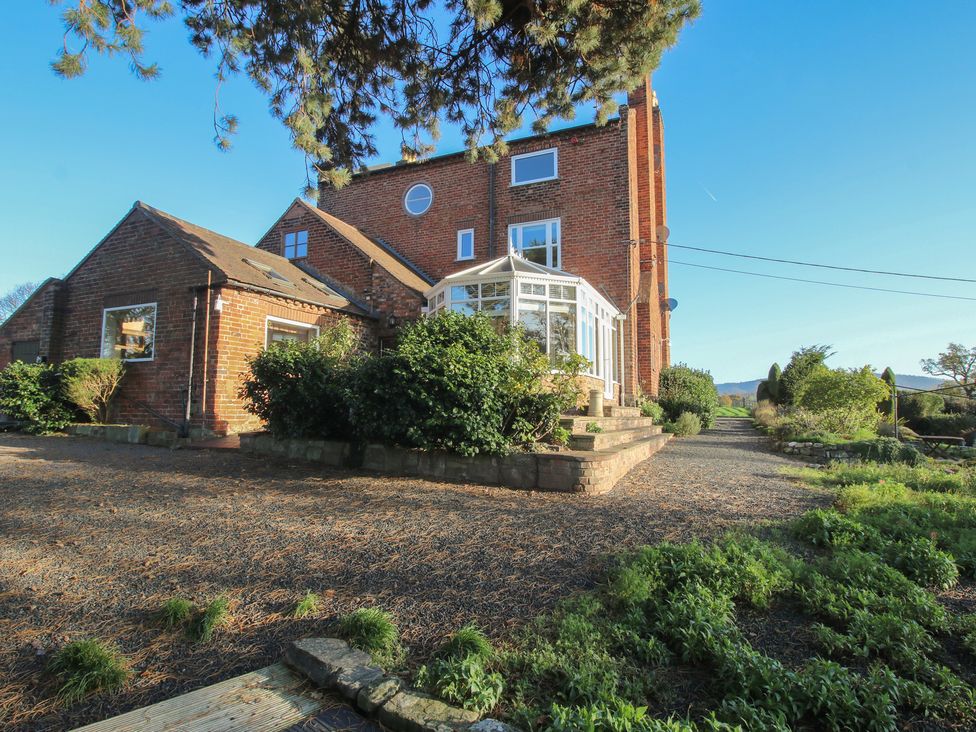 An outdoor view of a house with a conservatory and garden at The Mill House