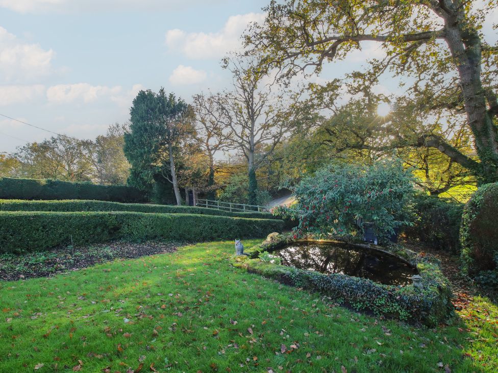 A garden with a pond and trees at The Mill House in 