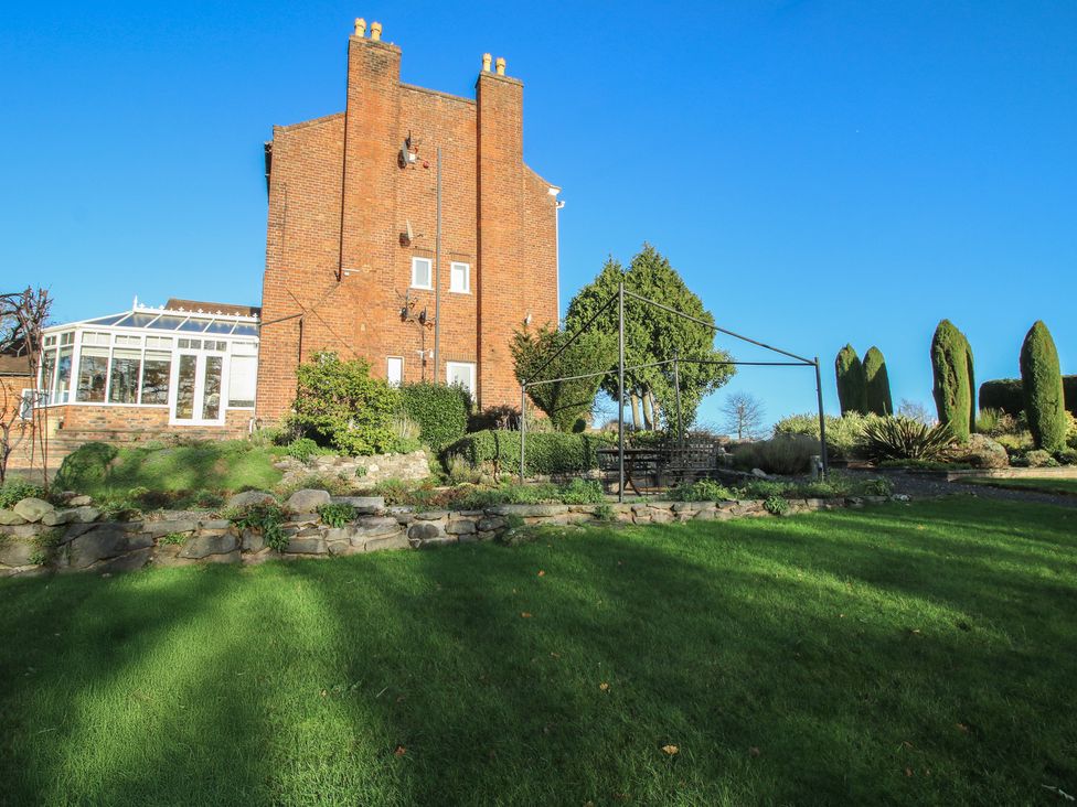 A garden with a house and conservatory at The Mill House 