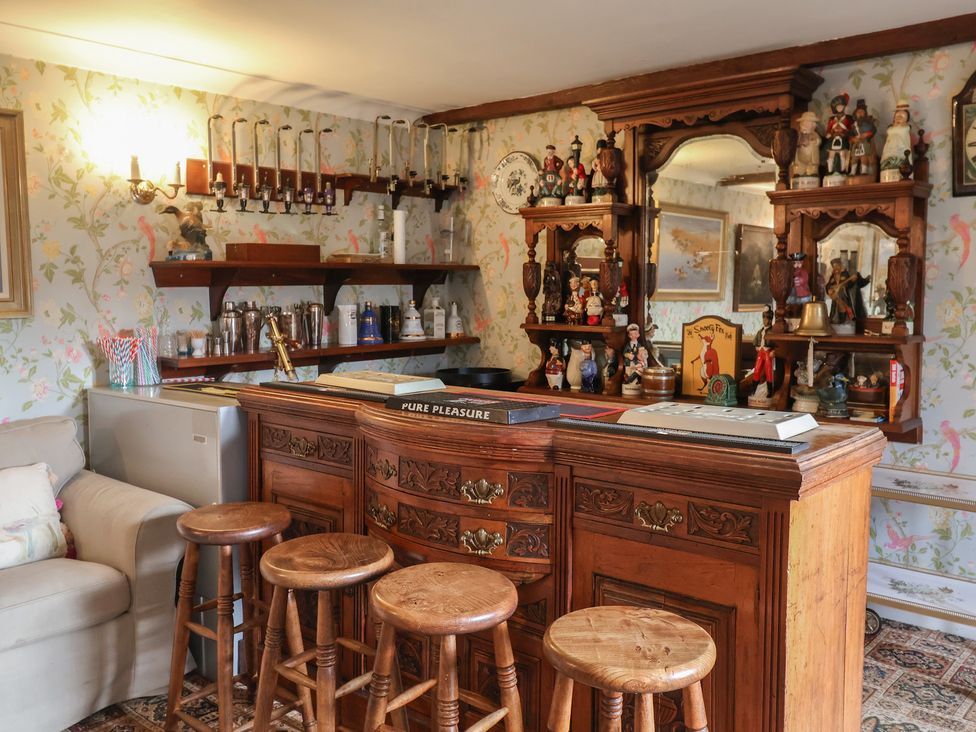 A home bar with stools and shelves displaying decorative items at Winston Lodge in Beccles