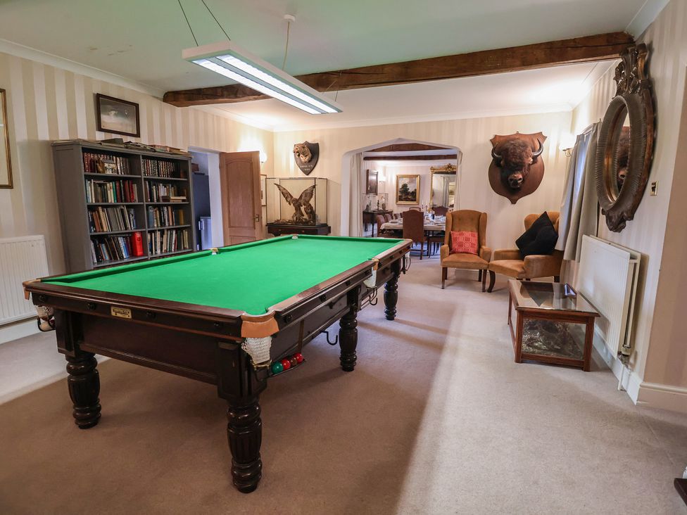 A snooker table with a bookshelf and armchair at Winston Lodge in Beccles