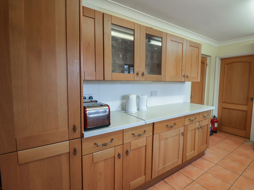 A kitchen with wooden cabinets and appliances at Winston Lodge in Beccles