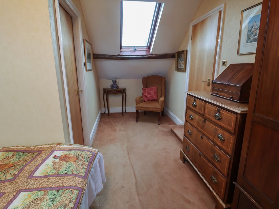 A bedroom with a bed, chair, table, and drawer at Winston Lodge in Beccles