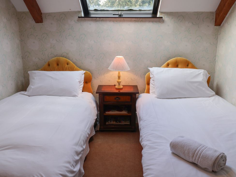 A bedroom with two single beds and a nightstand at Winston Lodge in Beccles
