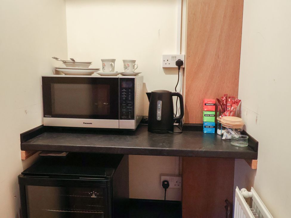 A kitchen corner with microwave kettle and cups at The Gun Room in Beccles