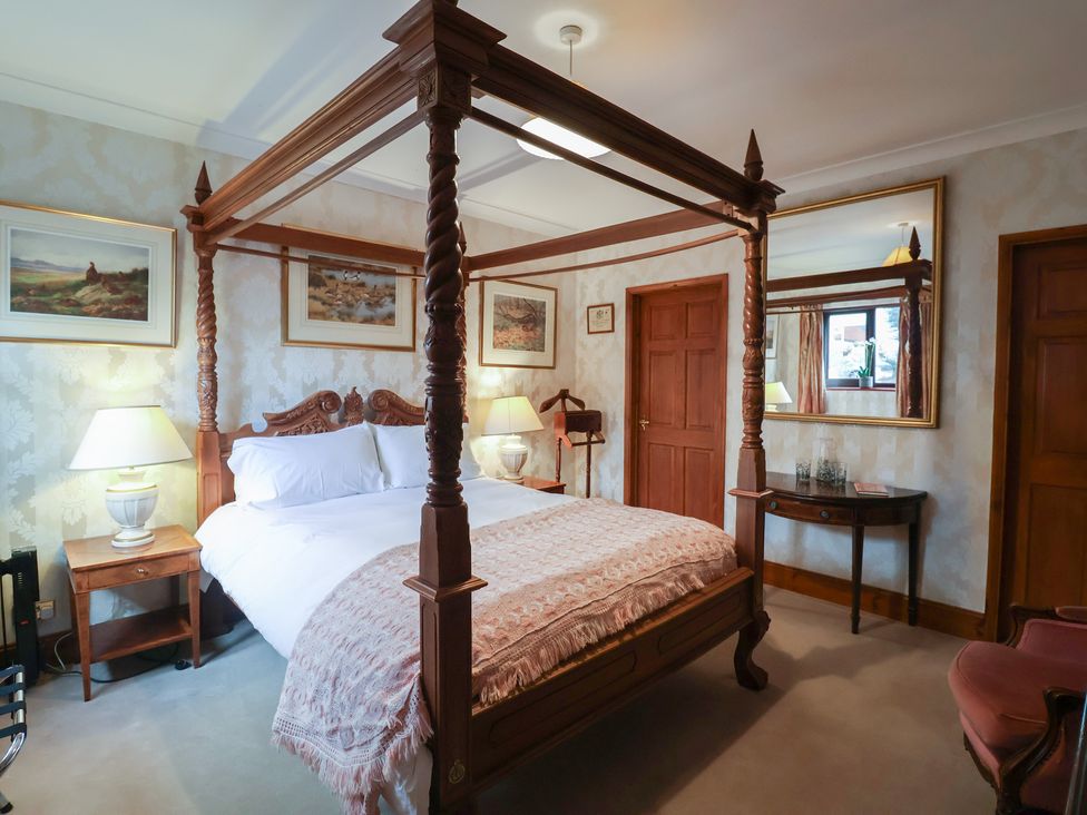A bedroom with a four-poster bed and lamps at The Gun Room in Beccles