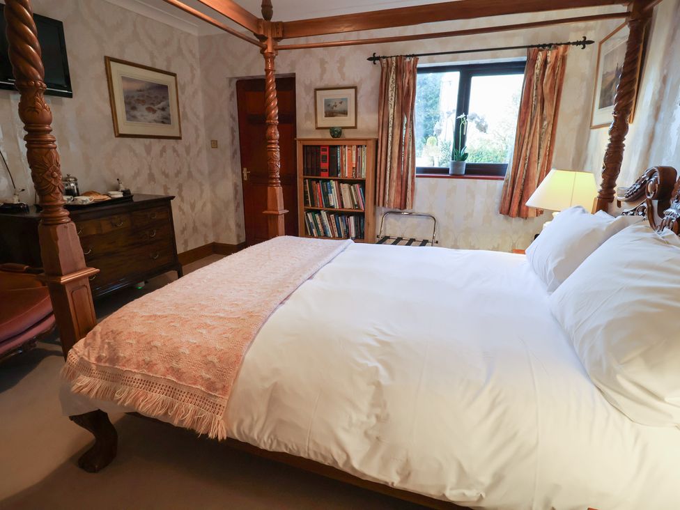 A bedroom with a bed, lamp, and bookshelf at The Gun Room in Beccles
