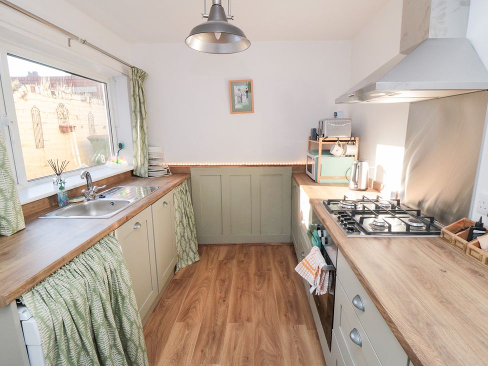 A kitchen with a sink and gas stove at Cattersty Cottage