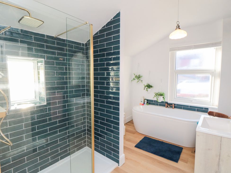 A bathroom with a shower, bathtub, and sink at Cattersty Cottage