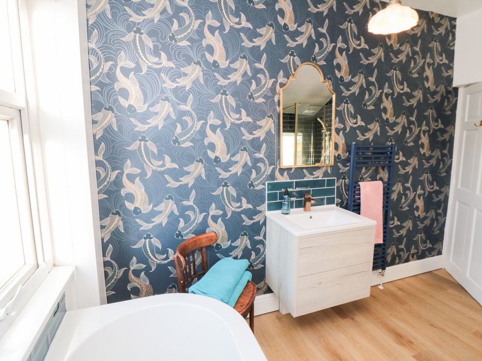 A bathroom with a bathtub and vanity at Cattersty Cottage