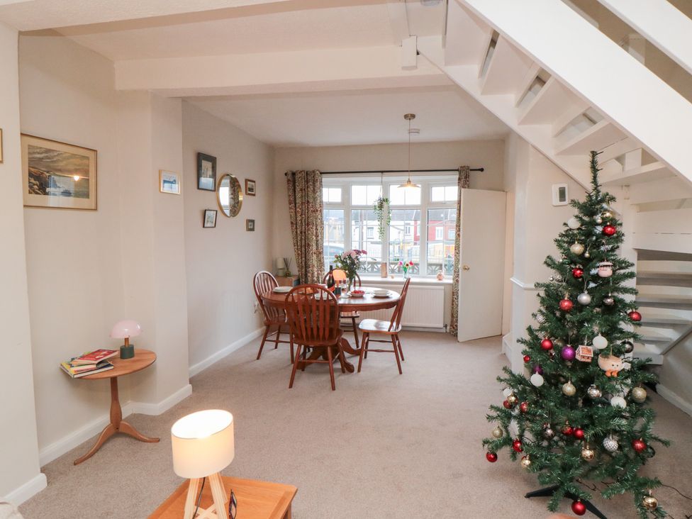 A dining room with a Christmas tree and dining table at Cattersty Cottage