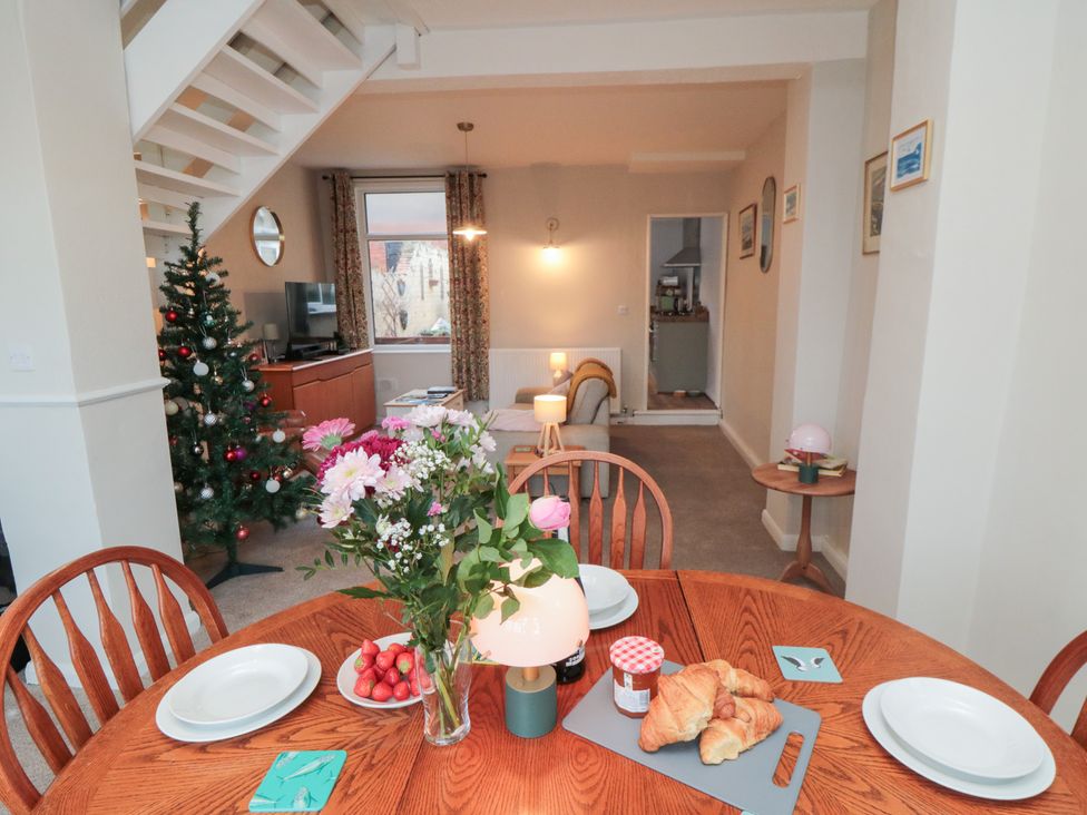 A dining room with a table set and a Christmas tree at Cattersty Cottage