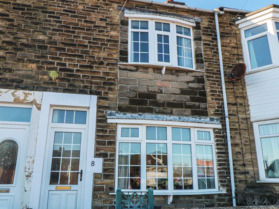 An exterior view of a house with brick wall and windows at Cattersty Cottage in Carlin How