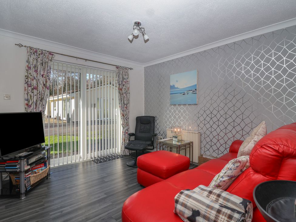 A living room with a red sofa and a television at Westview in Liskeard