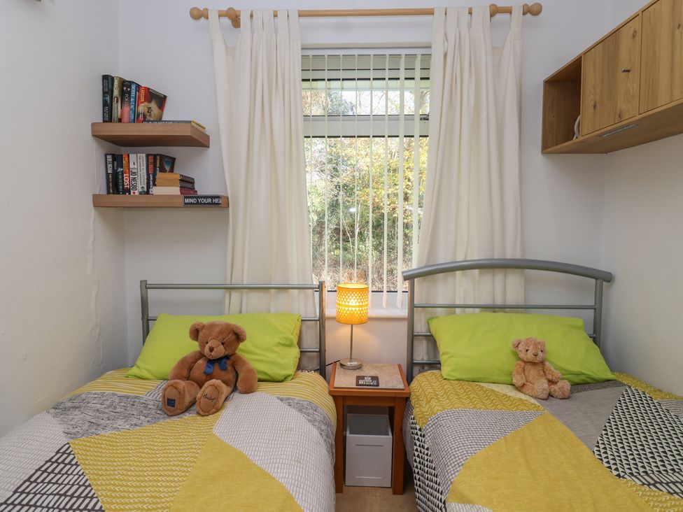 A bedroom with two beds and a bookshelf at Westview in Liskeard