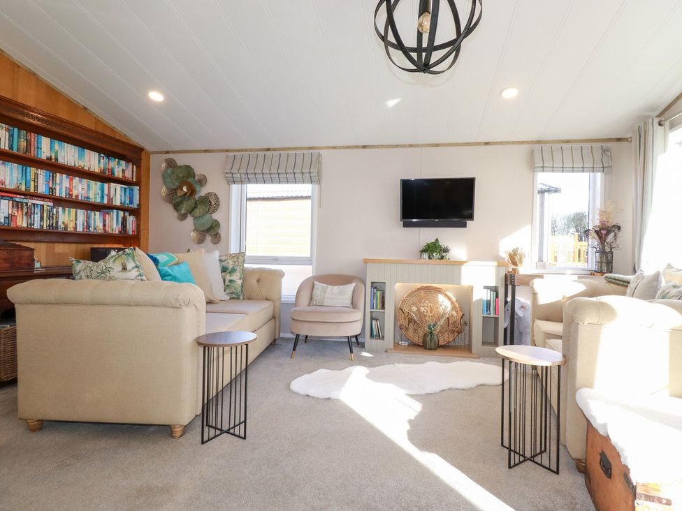 A living room with a sofa, armchair, and bookshelf at FW4 (Fairways 4)