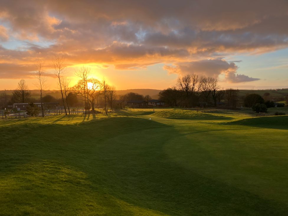 A sunset over a golf course with trees and hills at FW4 (Fairways 4) Doublebois near Dobwalls