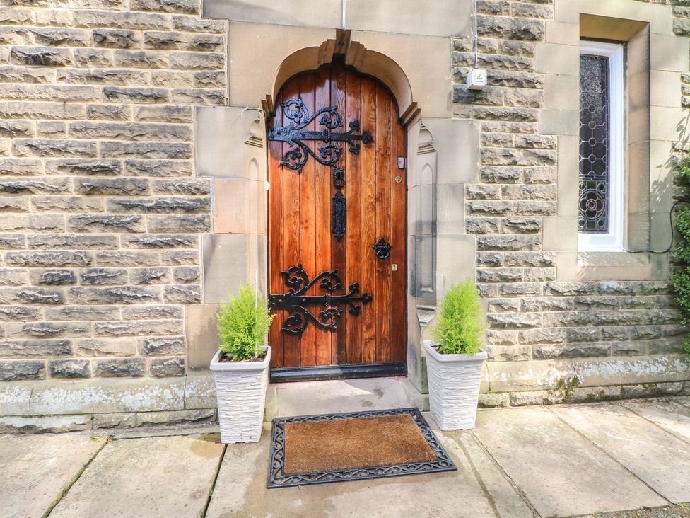 An entrance with a wooden door and stone wall at Beechwood House Hadfield
