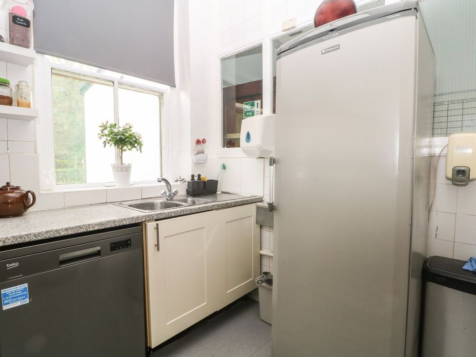 A kitchen with a sink, dishwasher, and refrigerator at Beechwood House in Hadfield