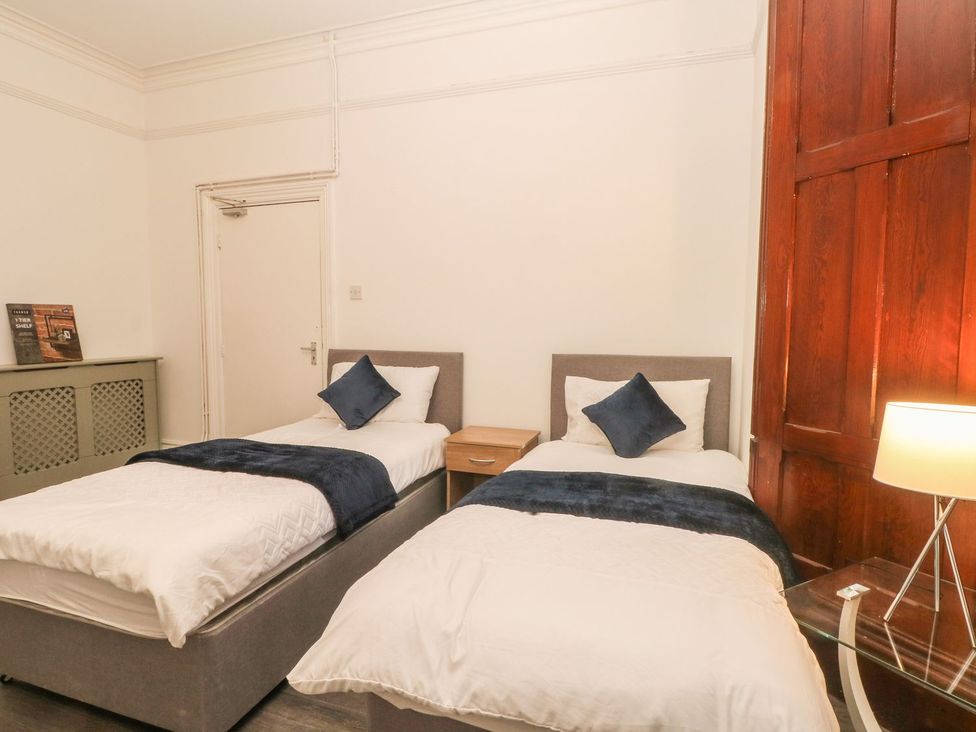 A bedroom with two single beds and a bedside table at Beechwood House in Hadfield