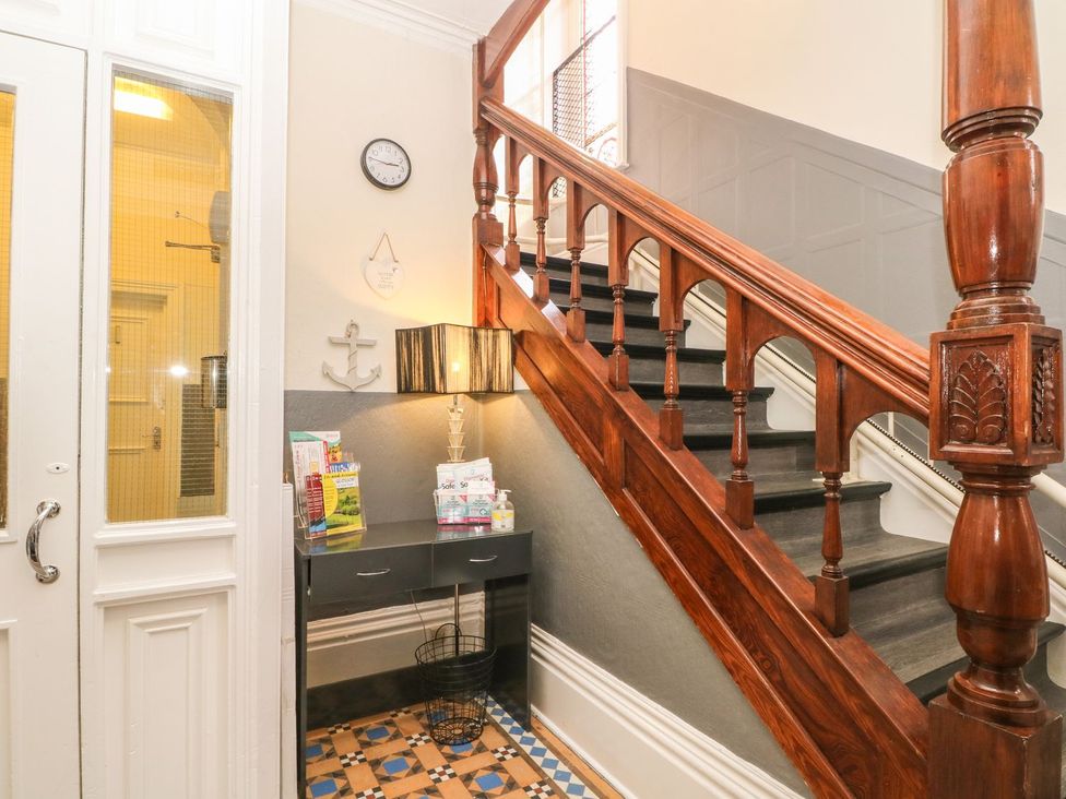A hallway with a staircase and console table at Beechwood House in Hadfield