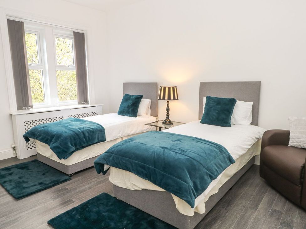 A bedroom with two beds and a chair at Beechwood House in Hadfield