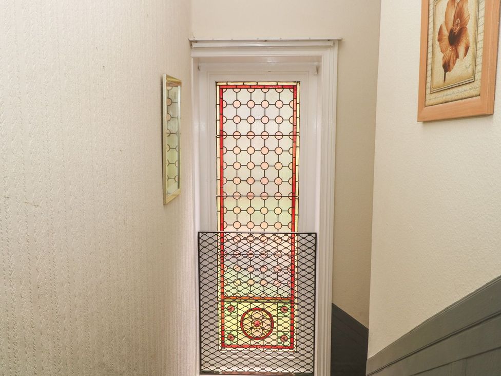 A hallway with a stained glass door and a mirror at Beechwood House in Hadfield