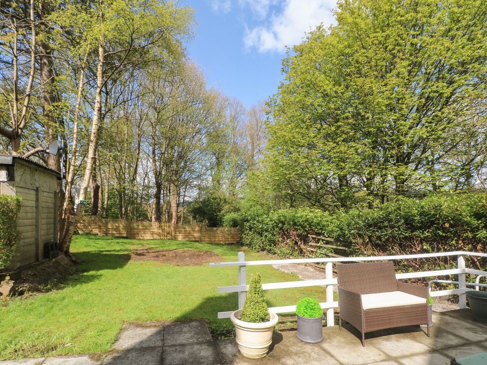 A garden with a patio and trees at Beechwood House in Hadfield