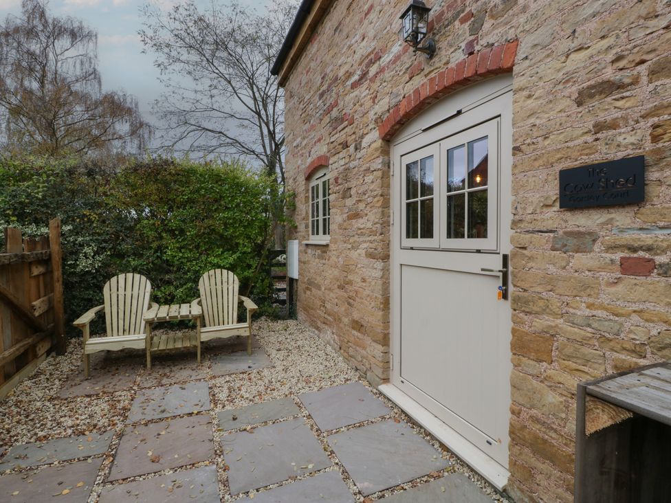 An outdoor area with chairs and a sign at The Cow Shed in Ross-on-Wye