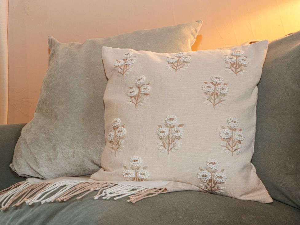 A cushion with floral design on a sofa at The Cow Shed in Ross-on-Wye