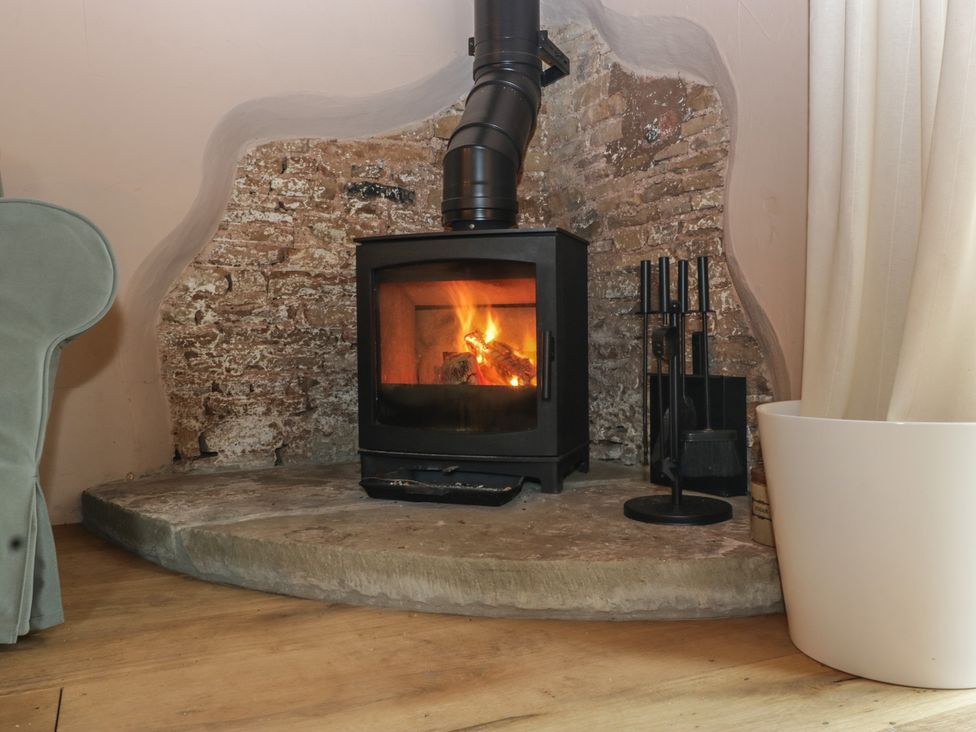 A living room with a wood stove and fire at The Cow Shed in Ross-on-Wye