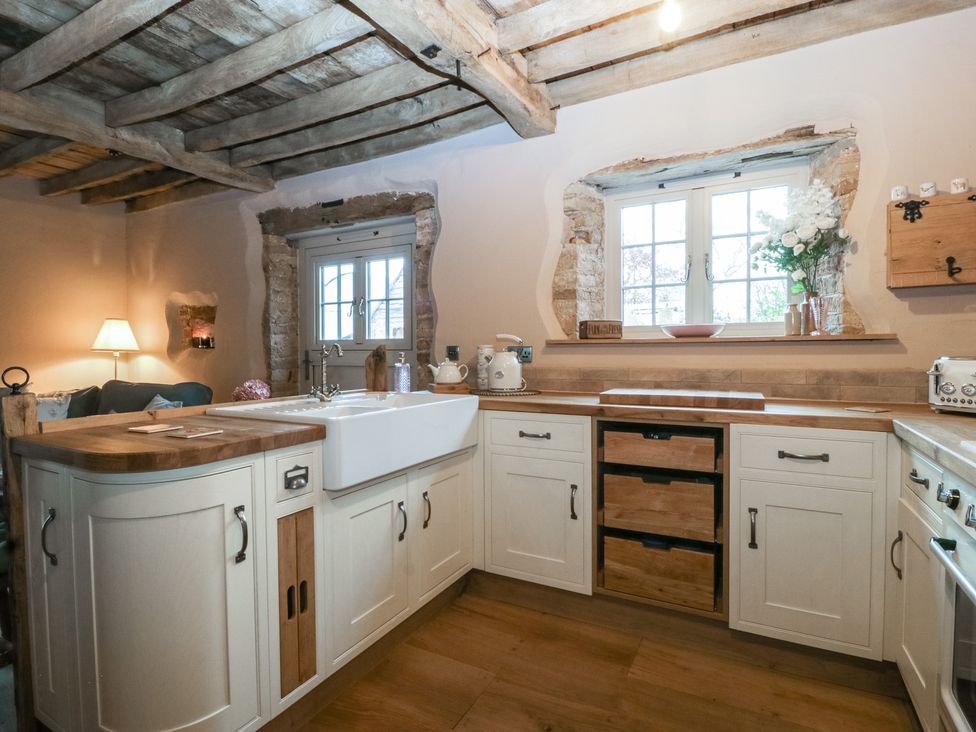 A kitchen with a sink, window, and white cabinets at The Cow Shed in Ross-on-Wye
