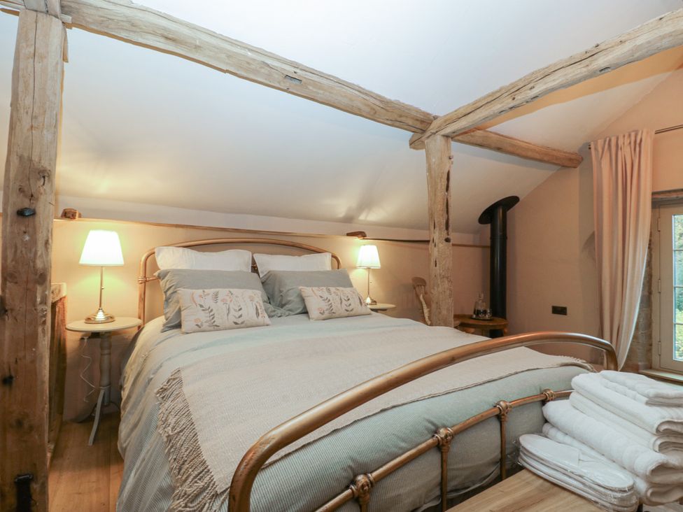 A bedroom with a bed and bedside lamp at The Cow Shed in Ross-on-Wye