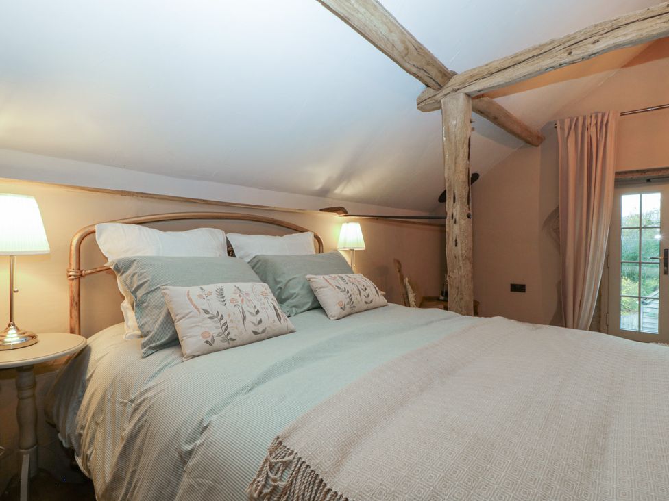 A bedroom with a bed and lamp at The Cow Shed in Ross-on-Wye