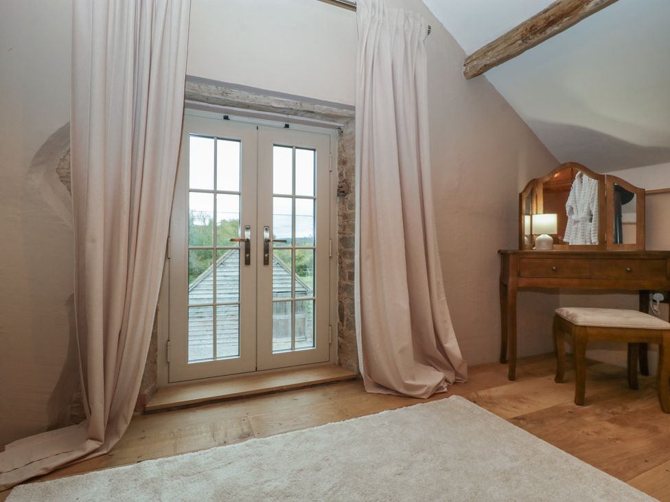 A bedroom with a double door leading outside and a vanity table at The Cow Shed in Ross-on-Wye