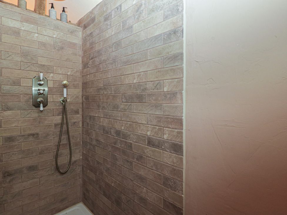 A shower with wall tiles and a shower head at The Cow Shed in Ross-on-Wye