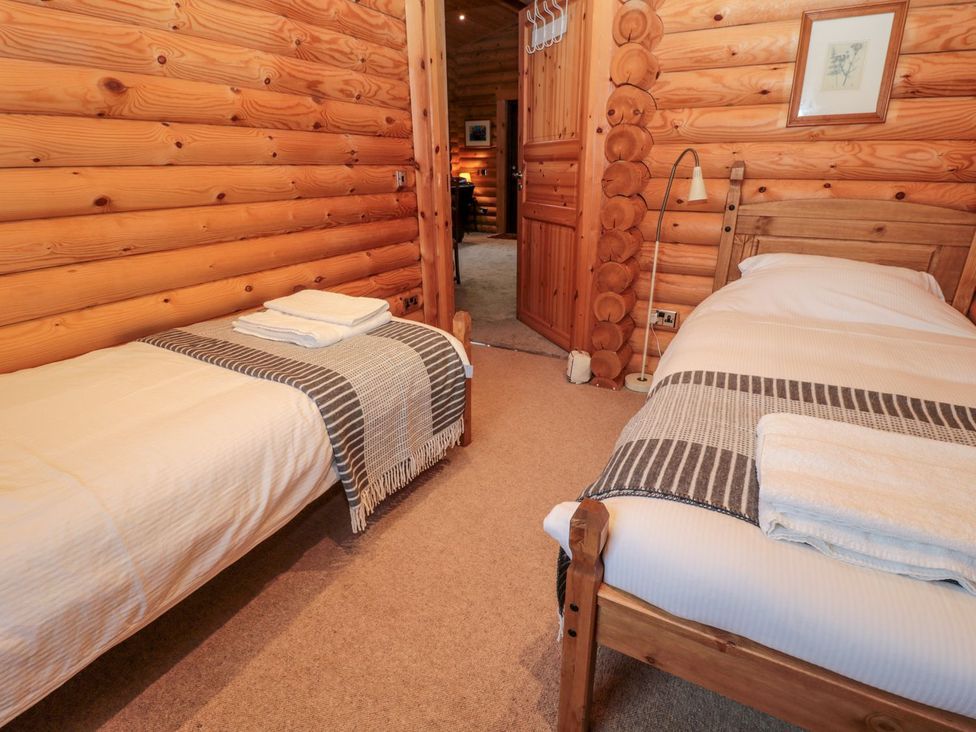 A bedroom with two beds and wooden walls at Little Bears Hideaway @ 23 Lakeside Felmoor Park near Felton
