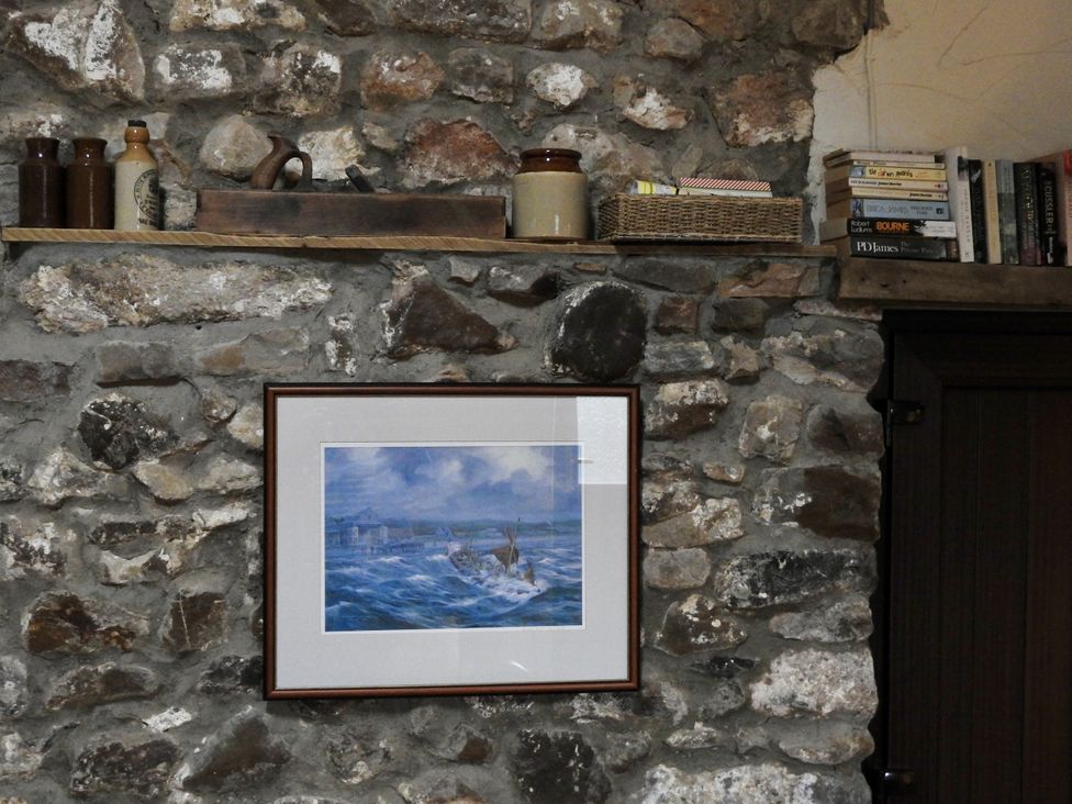 A shelf with bottles and books on a stone wall at Butterslade 