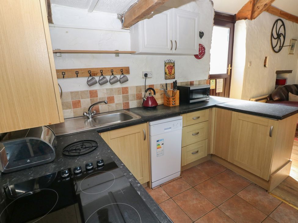 A kitchen with sink, kettle, microwave, and cooker at Butterslade Port Eynon