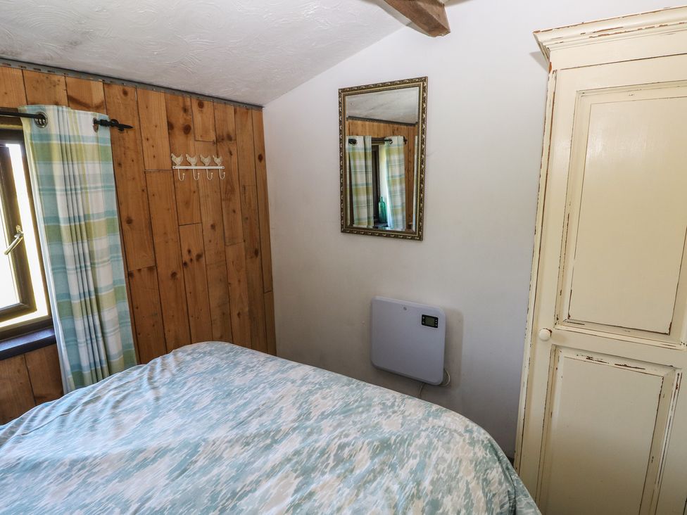 A bedroom with a bed and wardrobe at Butterslade in Port Eynon