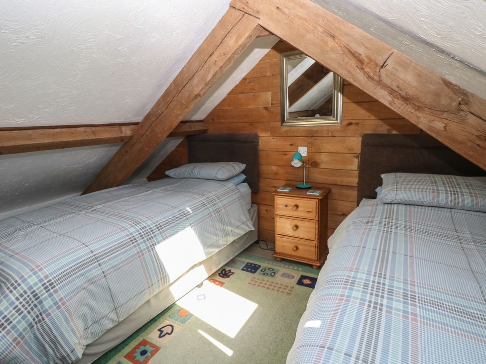 A bedroom with two beds and a nightstand at Butterslade in Port Eynon