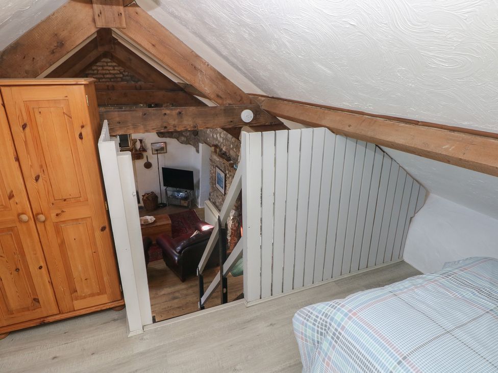 A loft with a wardrobe and bed at Butterslade in Port Eynon