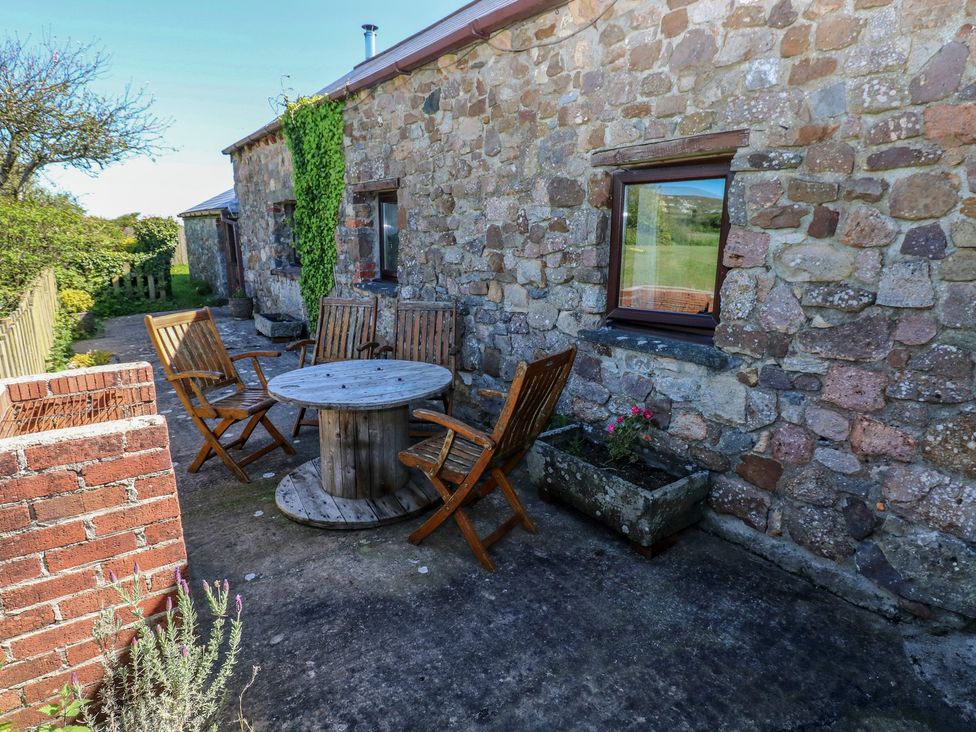 An outdoor seating area with a wooden table and chairs at Butterslade, Port Eynon